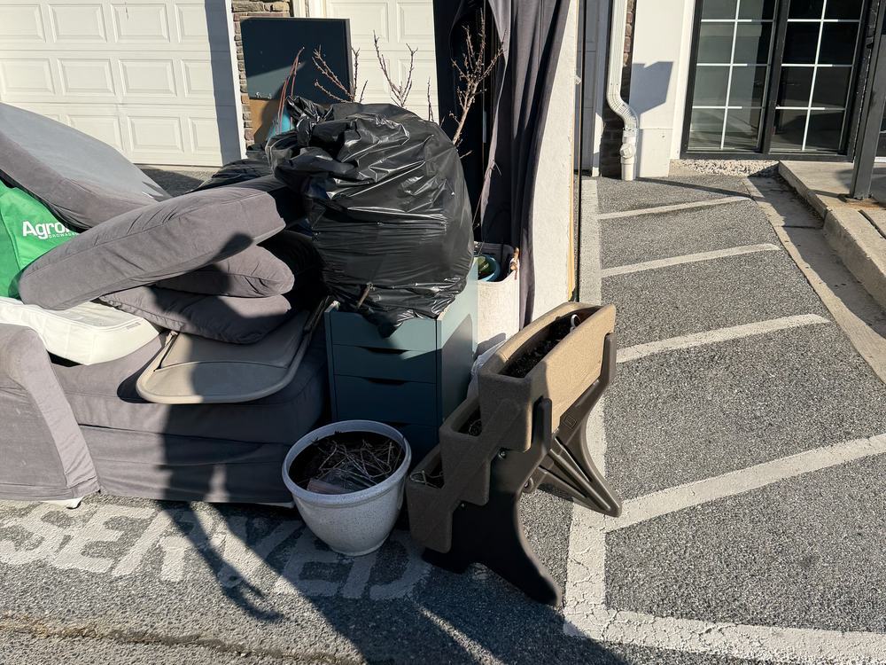 Curbside pile of a sofa, cushions, a dresser and bagged items before an apartment turnover on Greenfield Road in Elkridge, MD