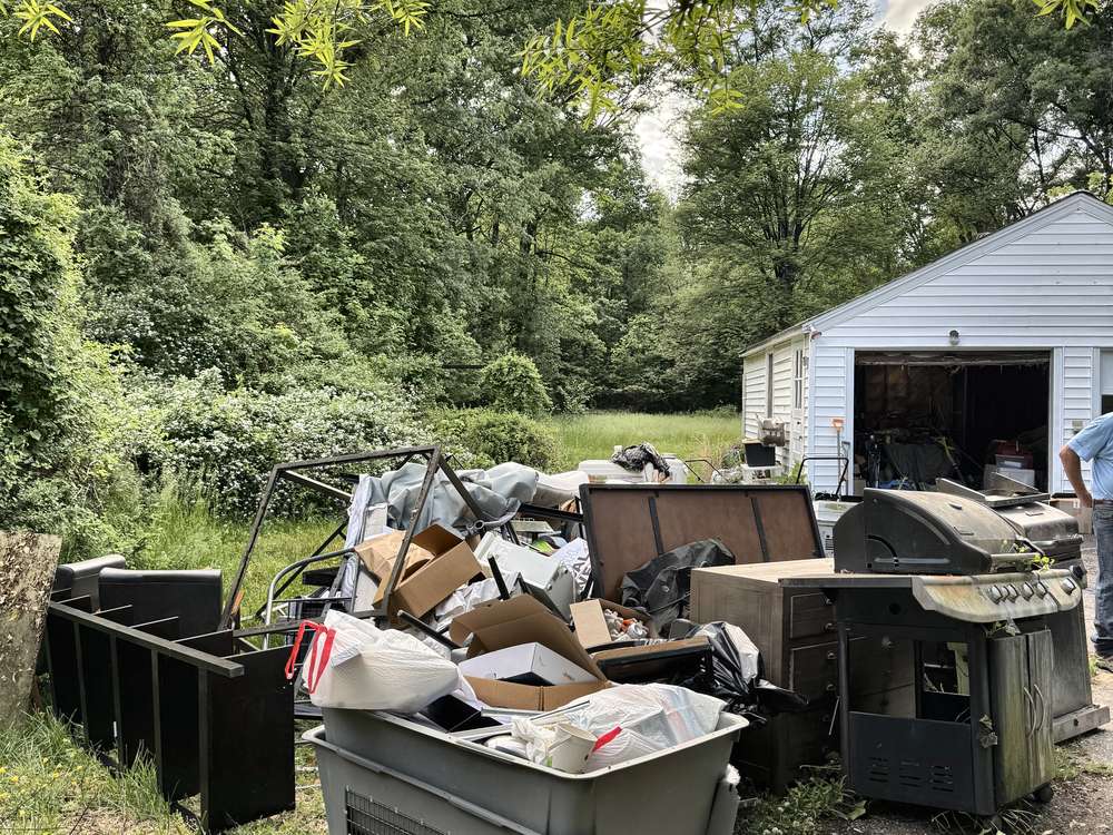 Estate belongings, a recliner, grill and patio set piled outside by a detached garage before an estate cleanout on Telegraph Road in Severn, MD