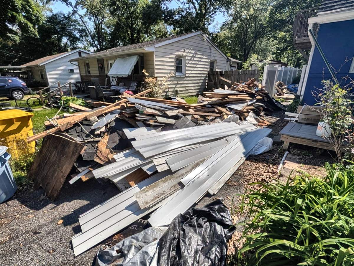 Pile of shed siding, framing lumber and roofing debris on a driveway after shed demolition in Severna Park, MD